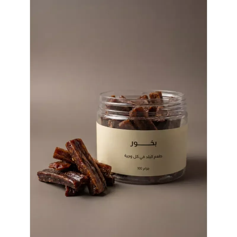 برطمان بخور معطر من سدرة بجانب مبخرة ذهبية على خشب طبيعي مع بتلات ورد مجففة، يعكس أجواء الفخامة.